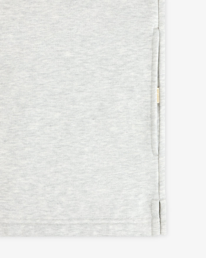 Close-up of the Aimé Souvenir Quarter Zip’s light grey fabric, side seam, hem, and small beige tag on the edge.