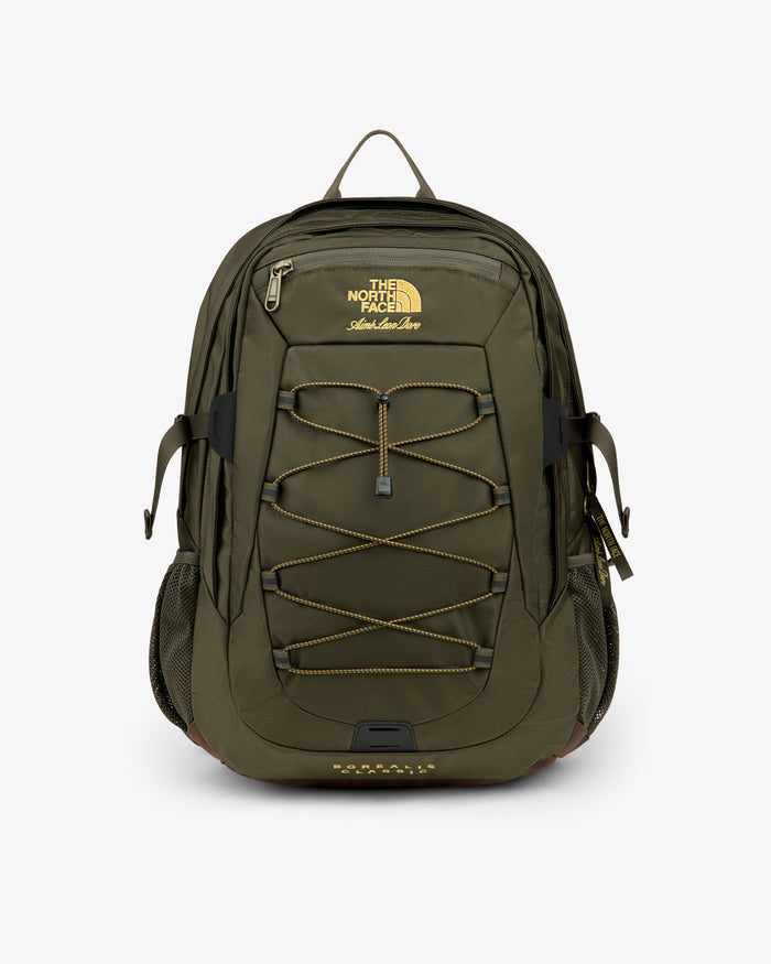 Olive green ALD / The North Face Borealis Backpack with bungee cord, side pockets, and yellow logo on white background.