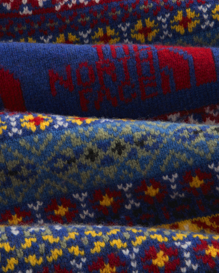 Close-up of the ALD / The North Face Fair Isle Scarf, featuring colorful patterns and red logo on a blue background.