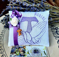Bomboniere religiose per bambino, bomboniere religiose per bambina, bomboniera Francescana,  Il  piccolo cuscino in  stoffa di colore chiaro e ricamo viola. Il ricamo del cuscino con lavanda rappresenta un Tao e delle mani giunte Idee per bomboniere, bomboniere religiose, bomboniere Francescane, bomboniere con tao, regali religiosi, regali francescani. E' un articolo adatto come regalo e come bomboniera per Comunione, Cresima e altre cerimonie.