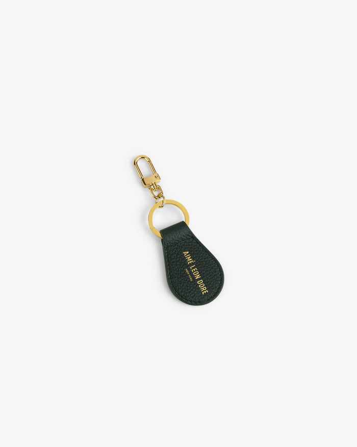 Dark green Leather Key Fob with gold ring, gold clasp, and Aimé Leon Dore text embossed in gold.