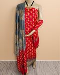 Red Katan silk unstitched suit set hand block printed with small golden yellow human figures in a dense all-over repeat, with grey panels, green accents and botanical and geometric border bands at the hem.