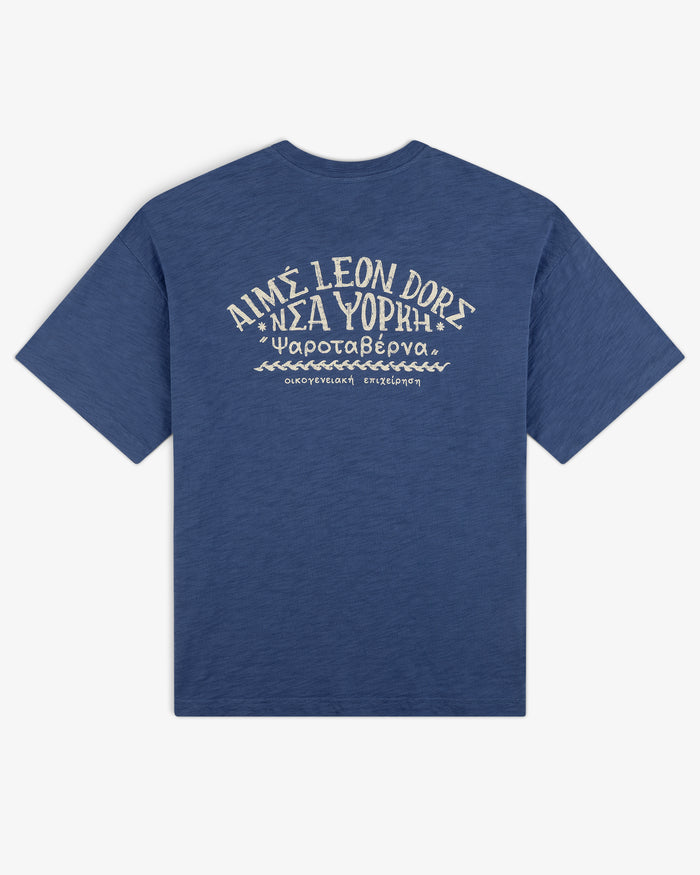 Taverna Tee: Blue shirt with white Greek and English text and graphics on back, reads AIMÉ LEON DORE ΝΕΑ ΥΟΡΚΗ.